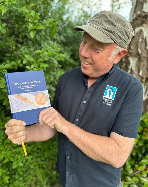Richard Baines holding a copy of his book the Rarity Garden